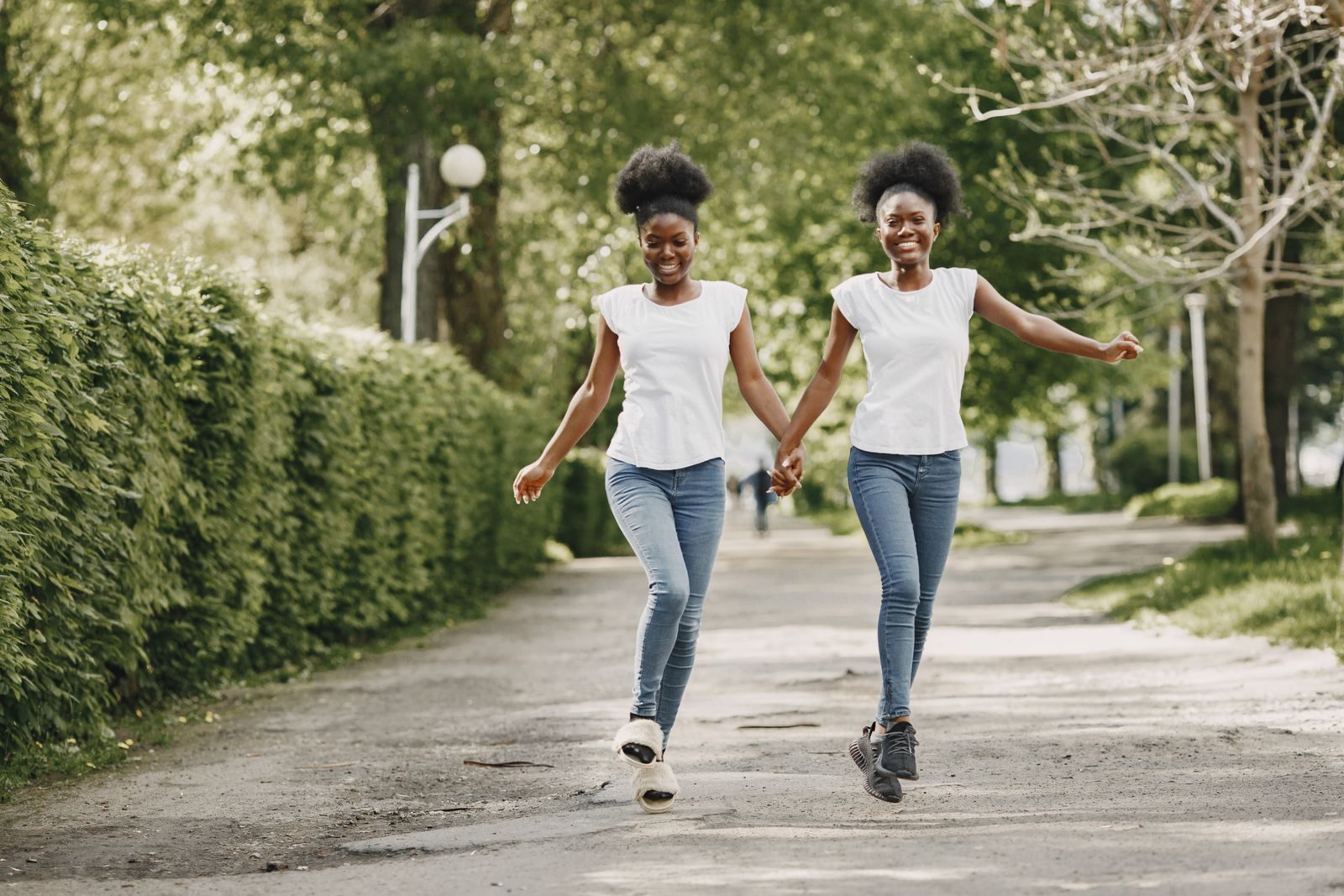 Two friends walking hand in hand down a tree-lined path